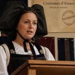 Femme en alsace costume traditionnel avec coiffe Schlupfkàpp et nœud noir